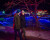 A couple is walking though the Nikka Yuko Japanese Garden during  the night at the winter lights festival. the tree is lit with a string of red lights and the other lights and plants can be seen behind it.